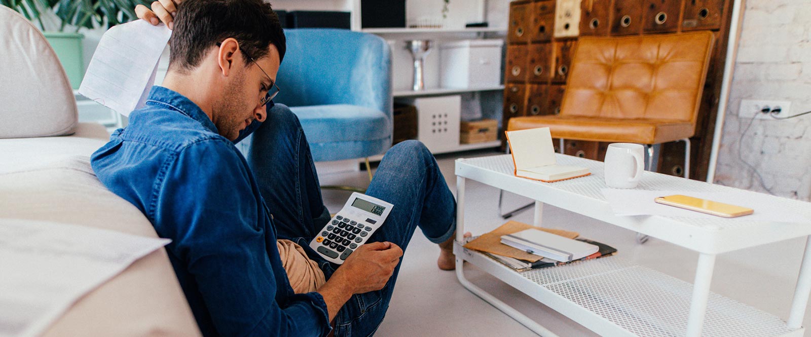 A young man using a calculator for financials in his home